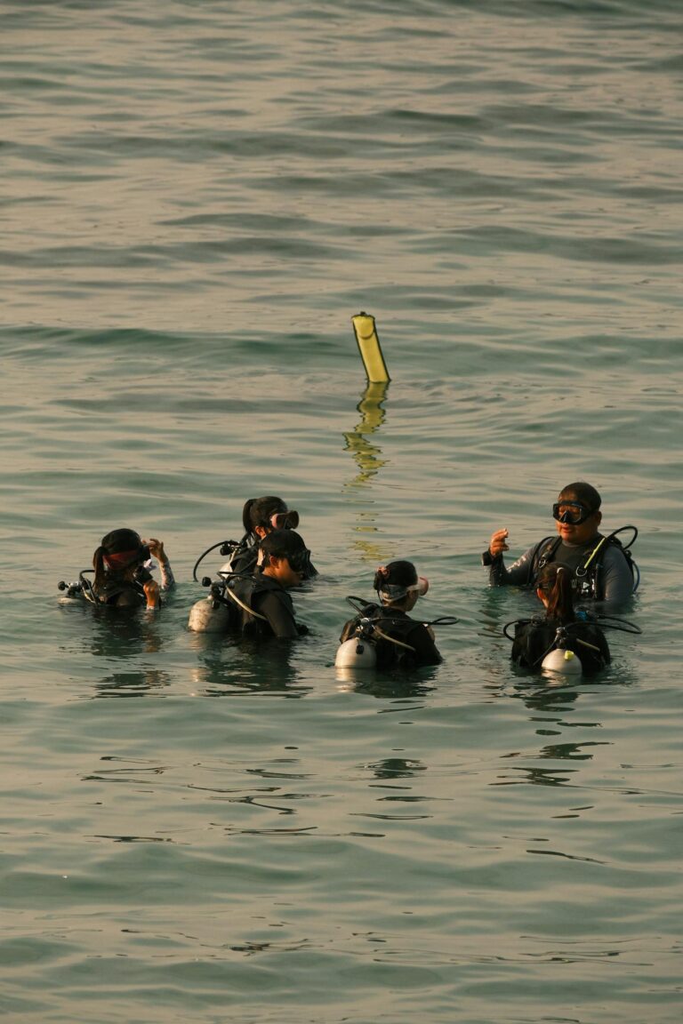 Scuba divers preparing for a dive in the ocean, focusing on teamwork and safety.